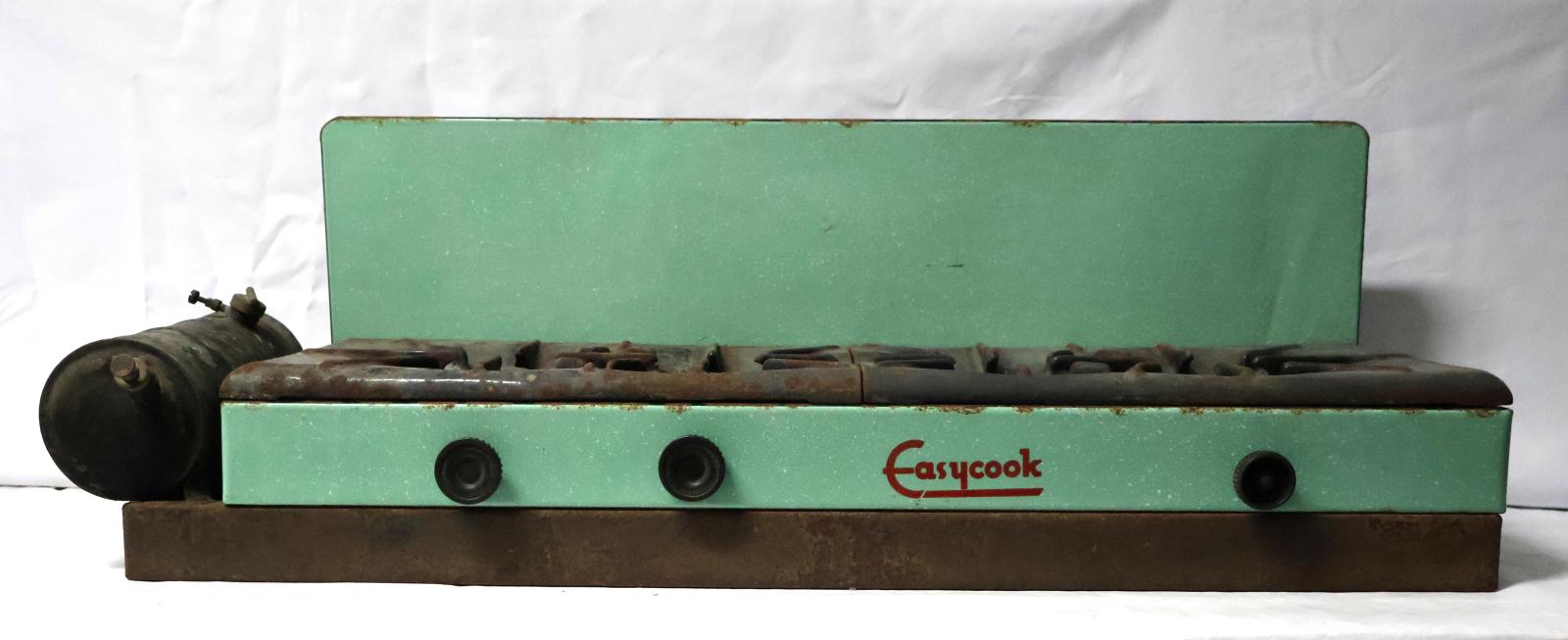 The front of the cooker which is green and cast iron, there is a fuel tank on the left hand side and three round black knobs on the front.