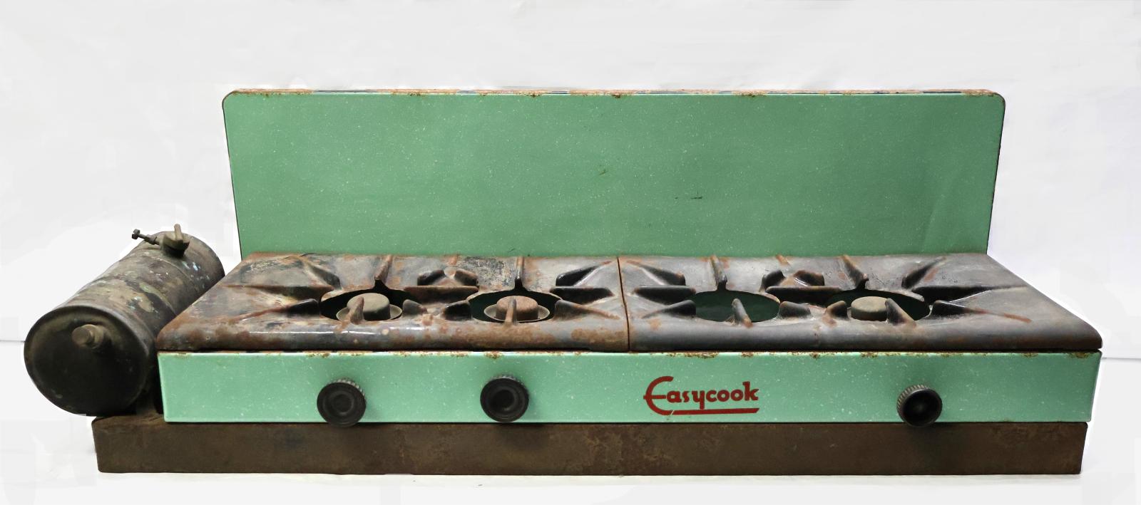 The front of the cooker which is green and cast iron, there is a fuel tank on the left hand side and three round black knobs on the front.