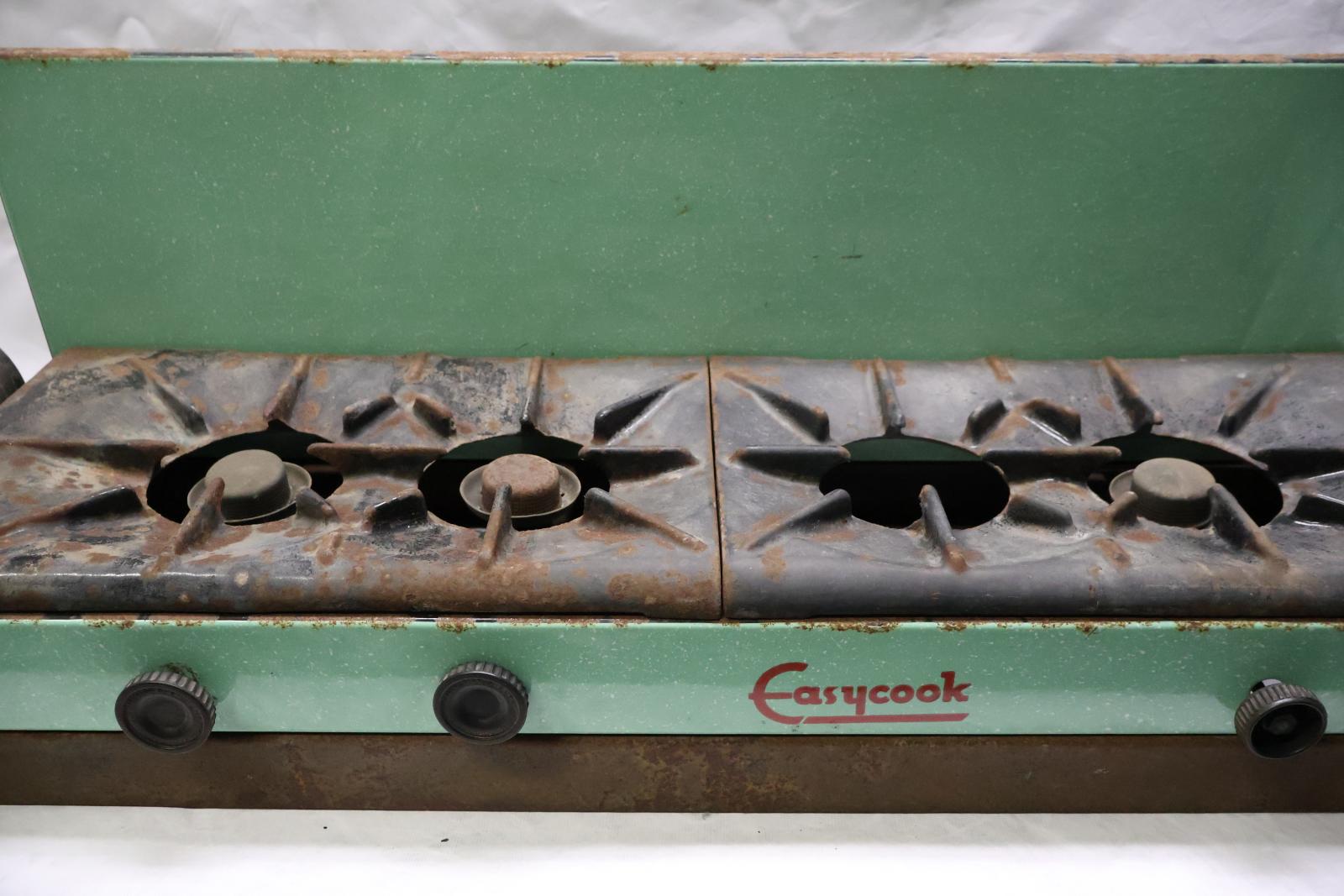 The front of the cooker which is green and cast iron, there is a fuel tank on the left hand side and three round black knobs on the front.
