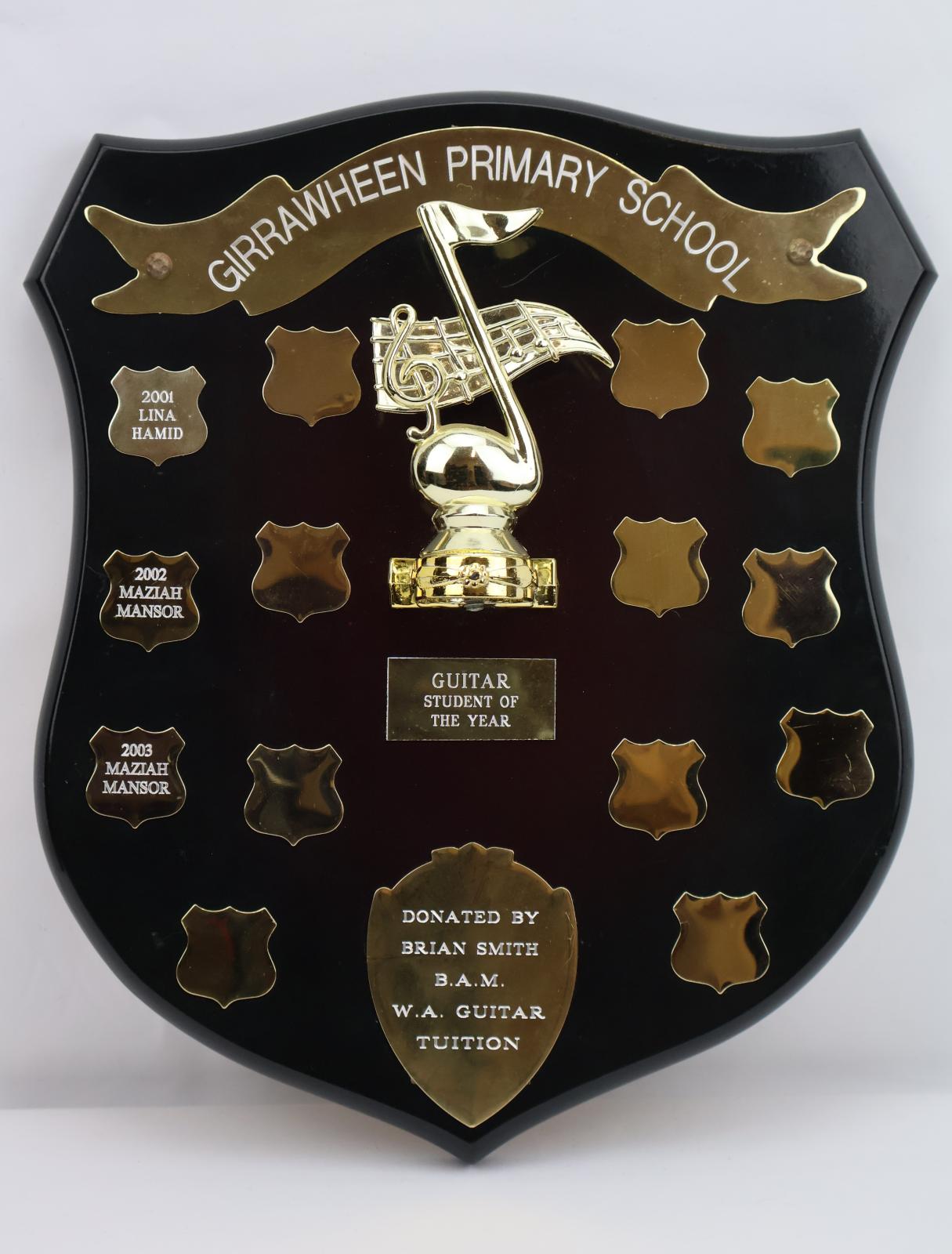 Brown wooden shield shaped plaque. Plastic banner across the top with “Girrawheen Primary School”. A rectangle banner with award title followed by a row with a single shield, then a row with four shields. At the bottom there is a rectangle with the sponsorship details.