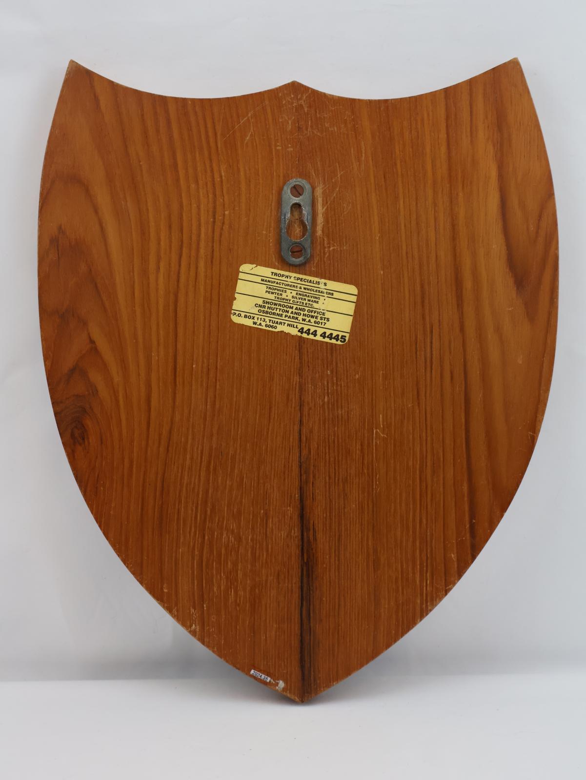 The back has an elongated oval shaped metal hanging attachment. There is a sticker in the centre of the back side.