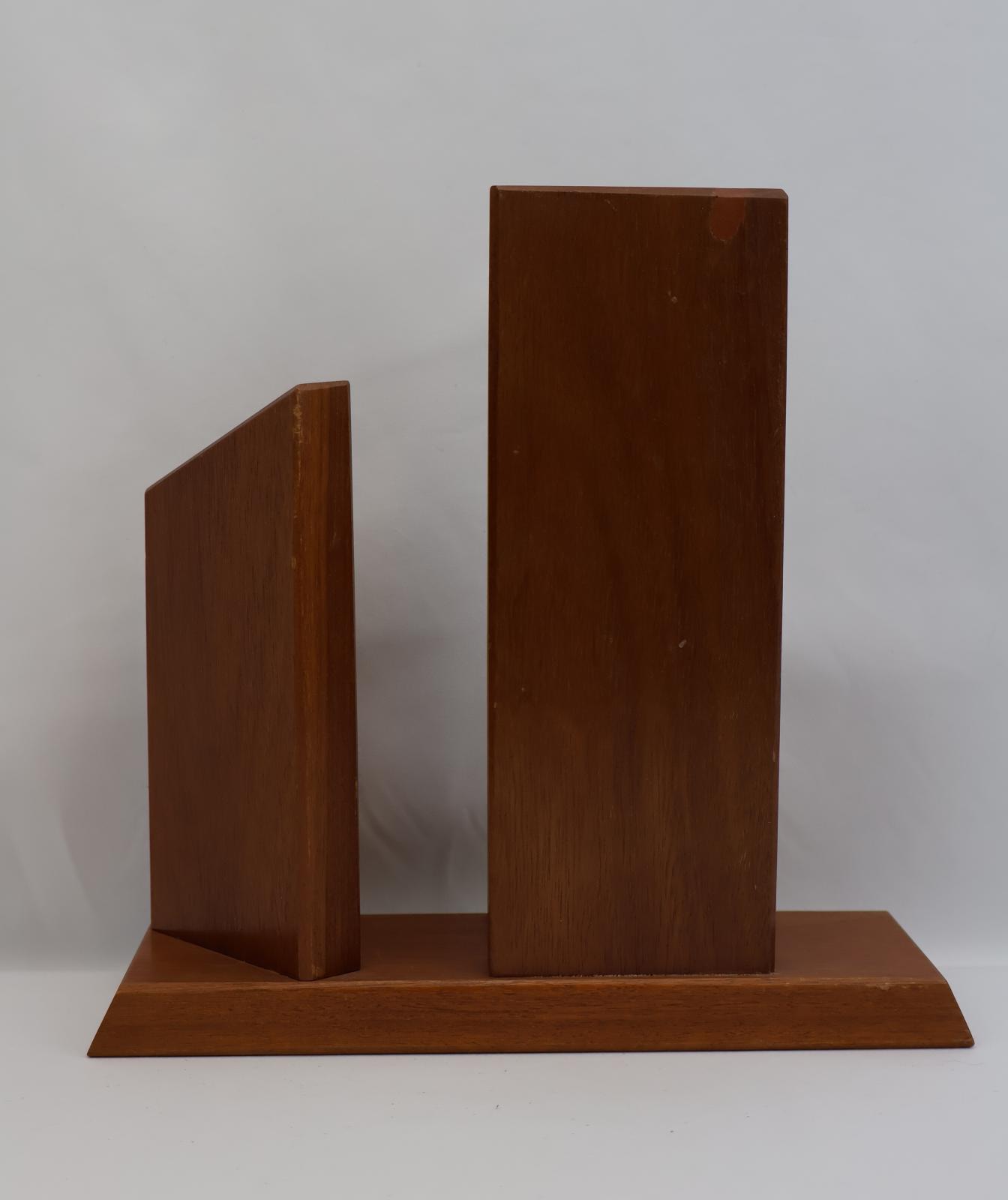 Rectangular base with one vertical rectangular piece attached at the back. There is another vertical rectangular piece but it has a diagonal top edge.
