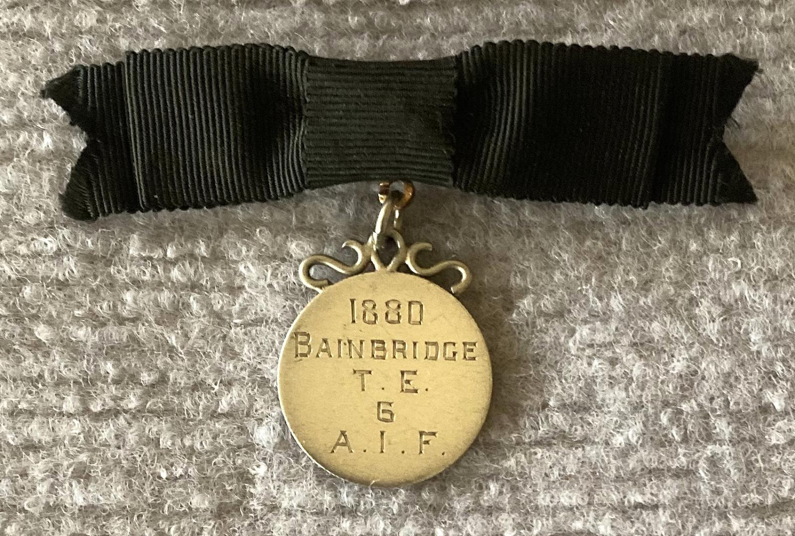 Identity badge made from coin suspended on black bow brooch