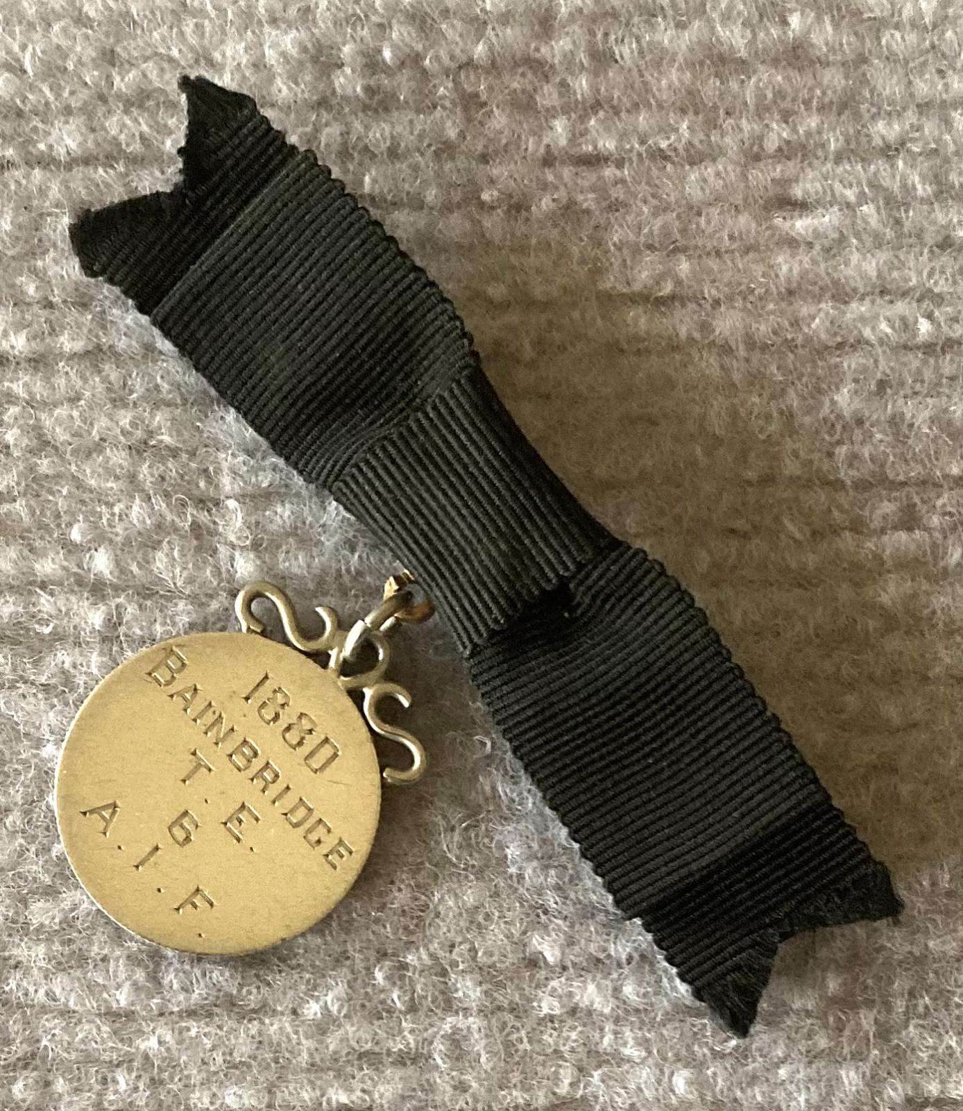 Angled view of identity badge made from coin suspended on black bow brooch