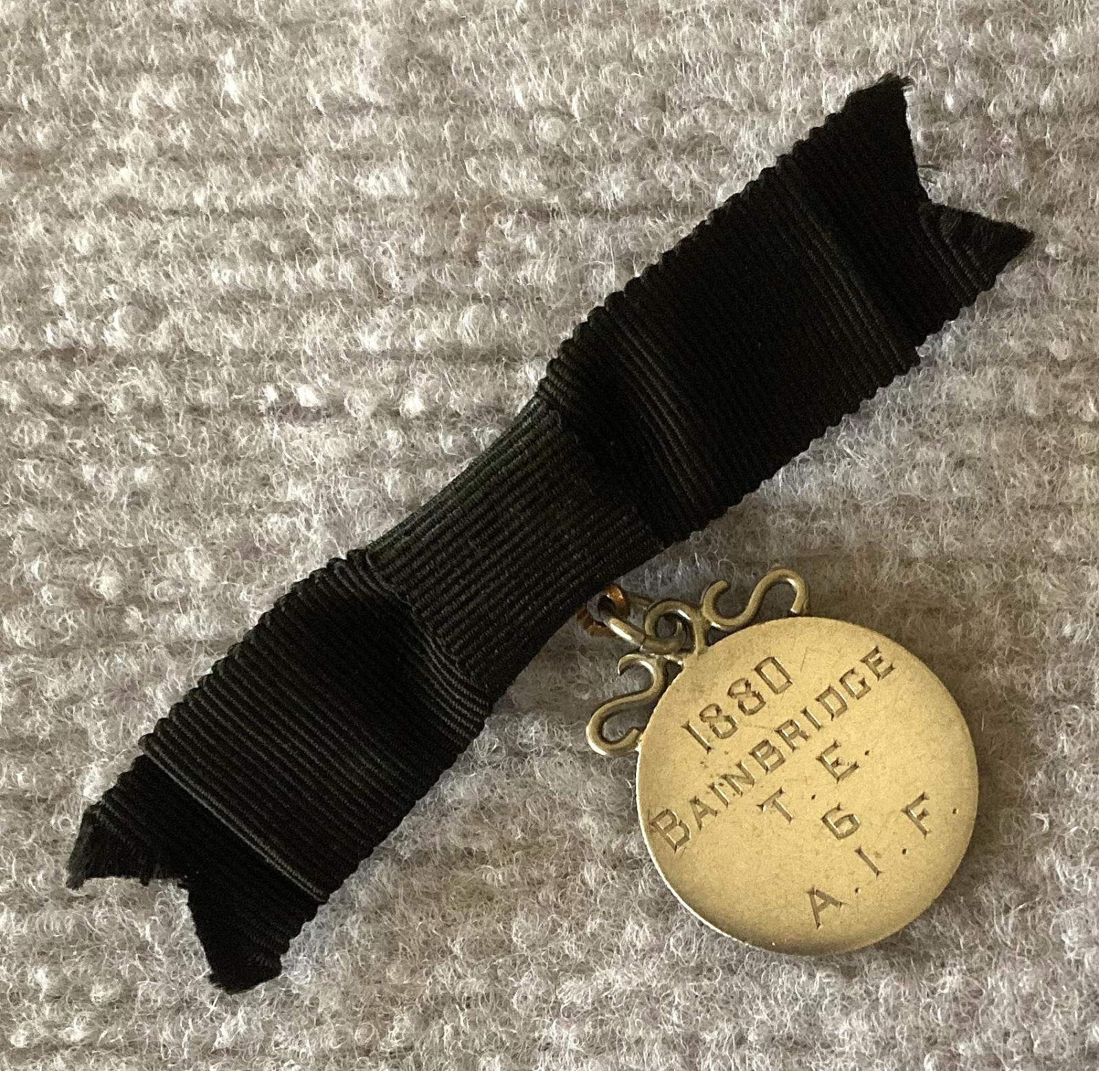 Other angled view of identity badge made from coin suspended on black bow brooch