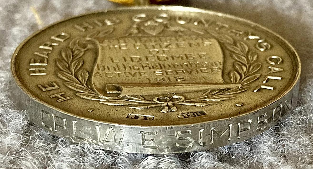 Close-up of end view of Welcome Home presentation medal from the Citizens of Lidcombe showing engraved name