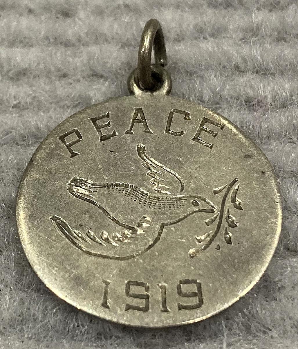 Oblique view of silver Peace medallion featuring dove carrying olive branch - 1919