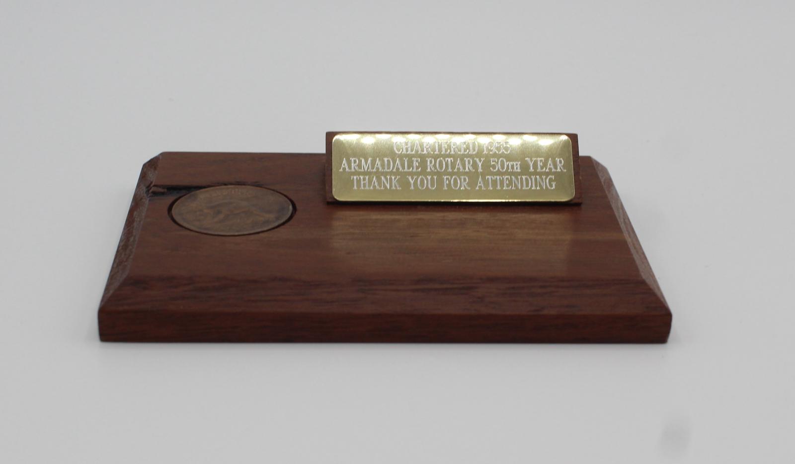 A small wooden plaque with an embedded penny and metal plate.