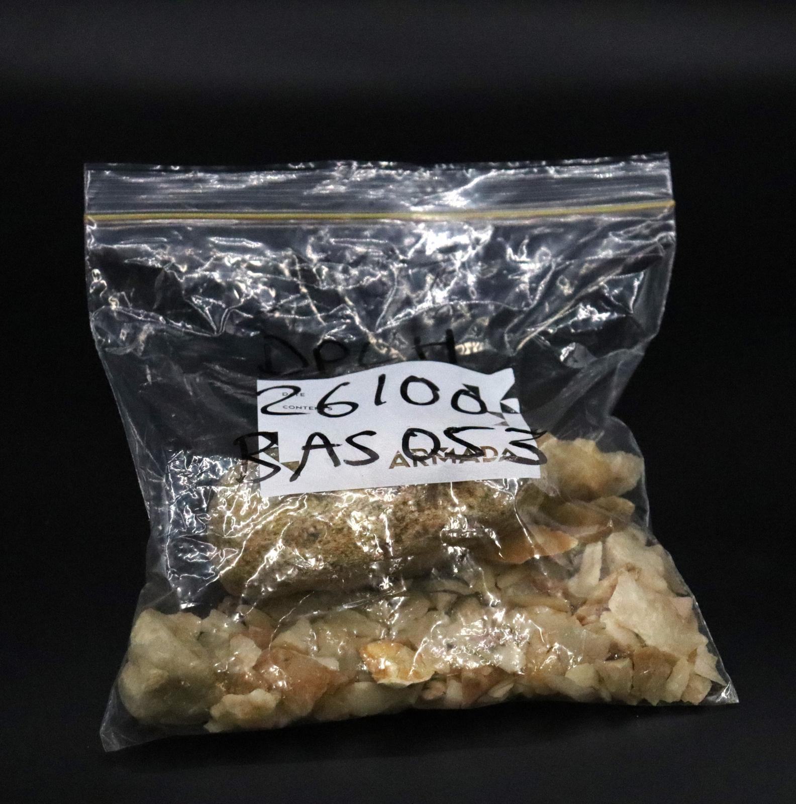The bag is half filled with a quantity of smaller sharp stones and a large rounder rock. 