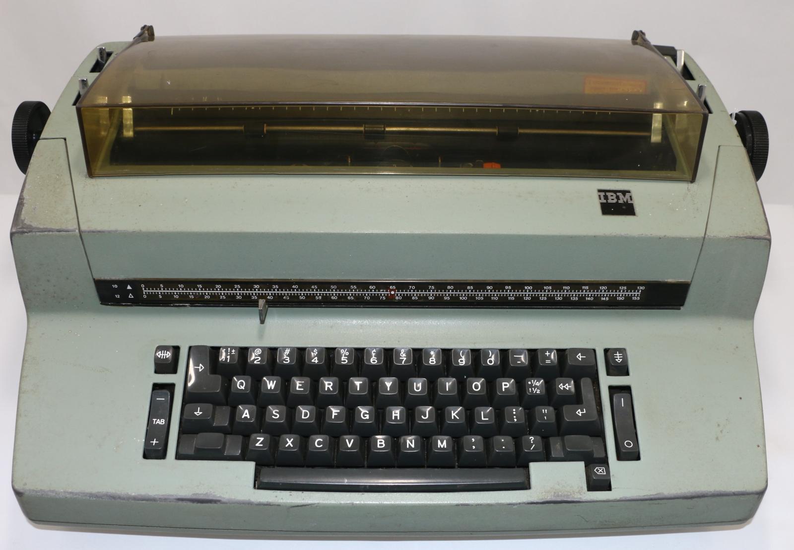 Large green electric typewriter. Keys are black and there is a clear grey cover at the top.