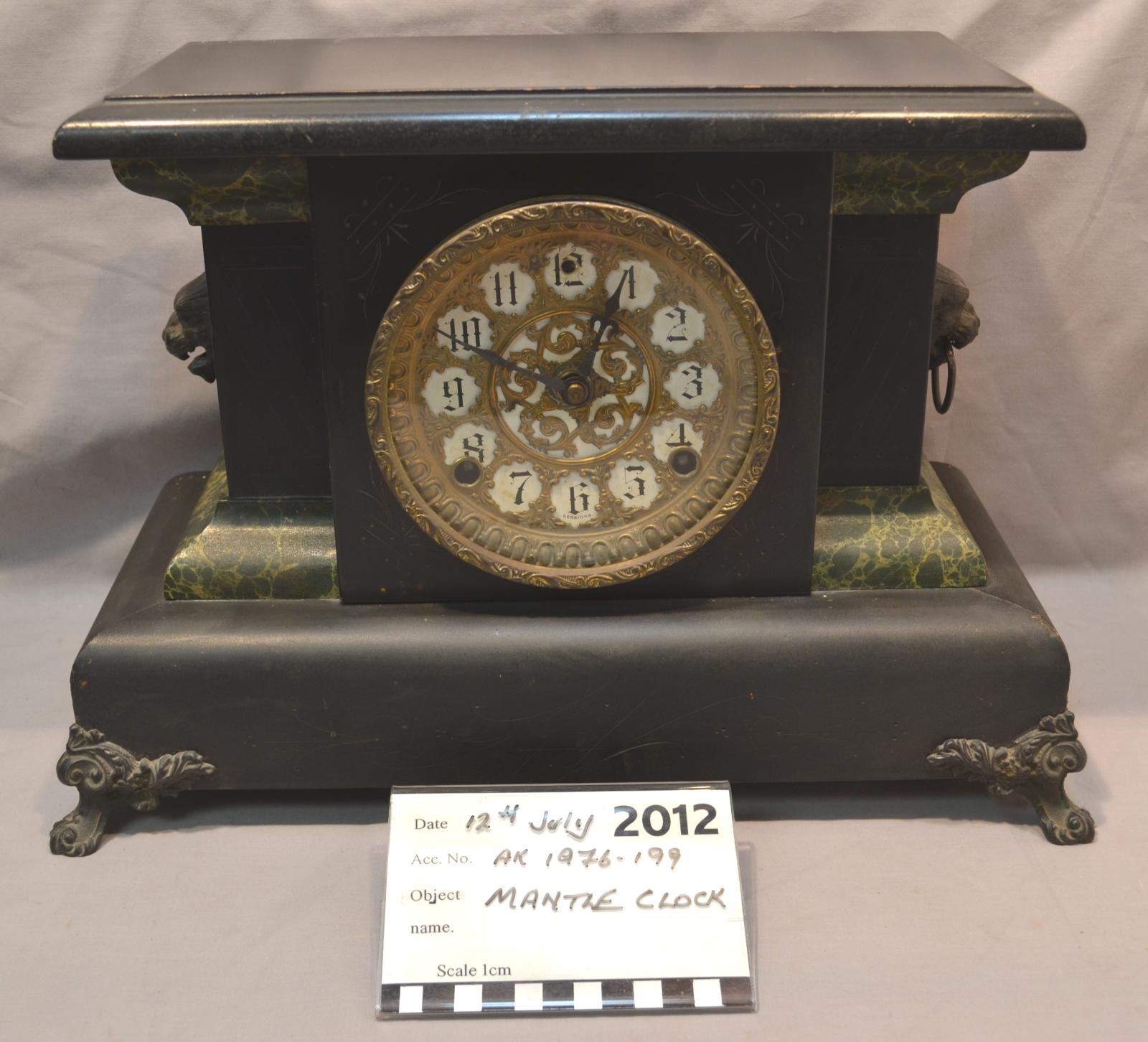 A rectangular mantle clock, finished in black lacquer and gilded with ornate gold-coloured metal.