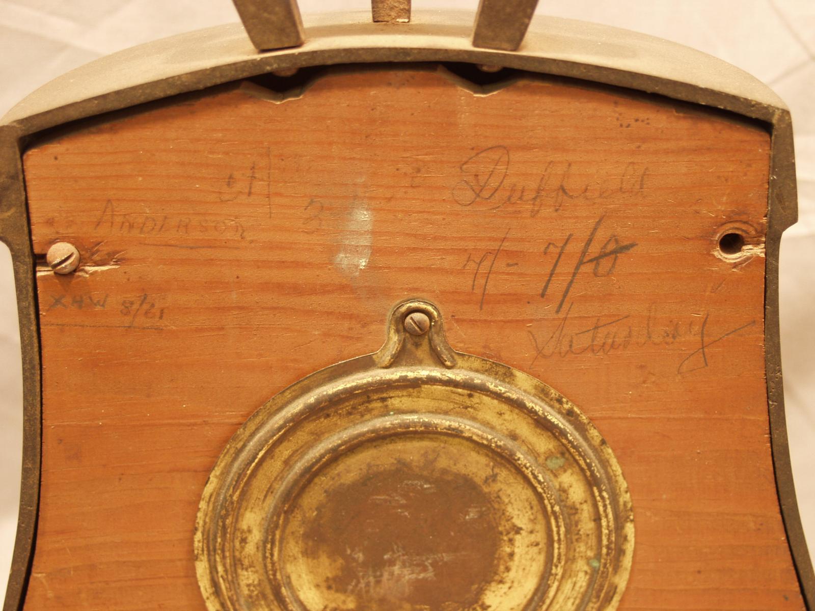 The pencil lettering on the wooden backside of the mantle clock.