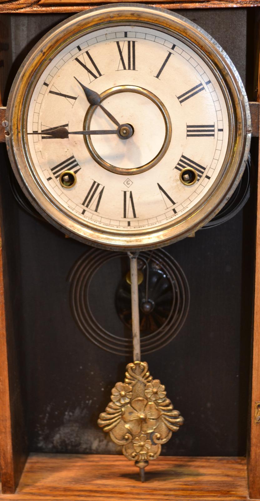 Close up of the clock face and pendulum with the glass door open.