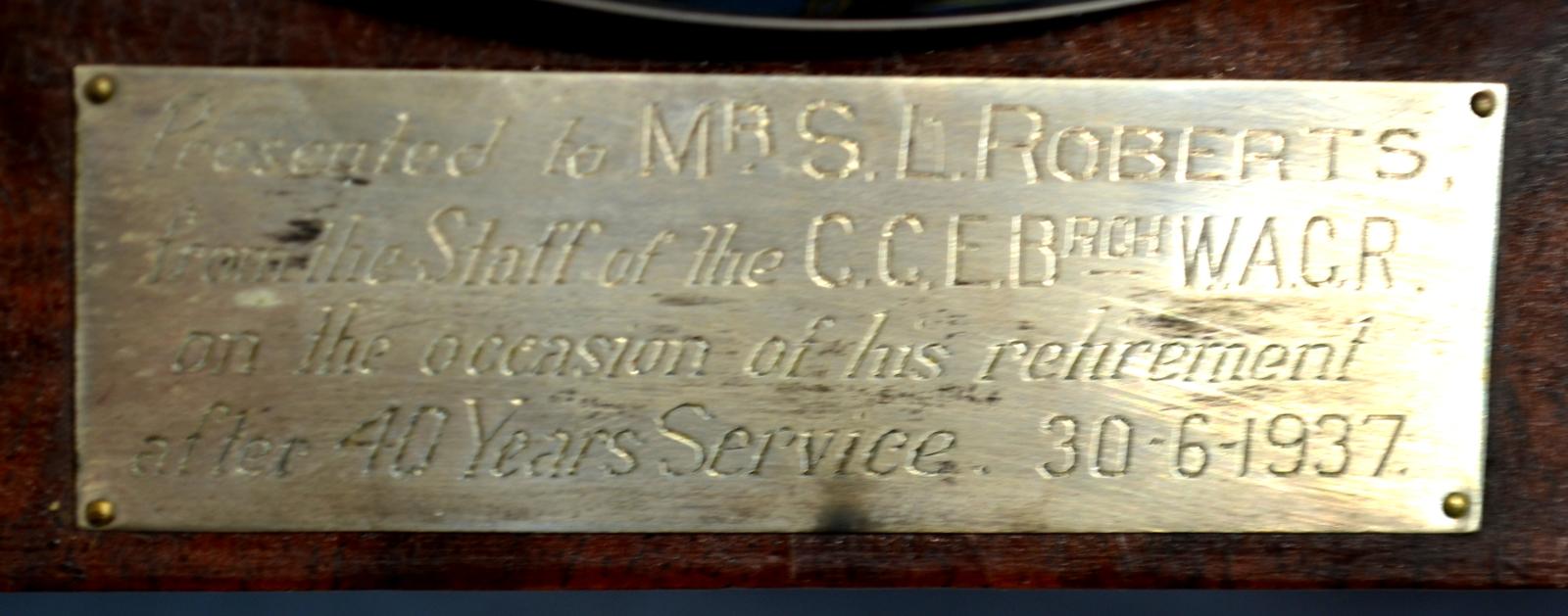 A rectangular, metal plaque on the front of the clock, located under the clock face.