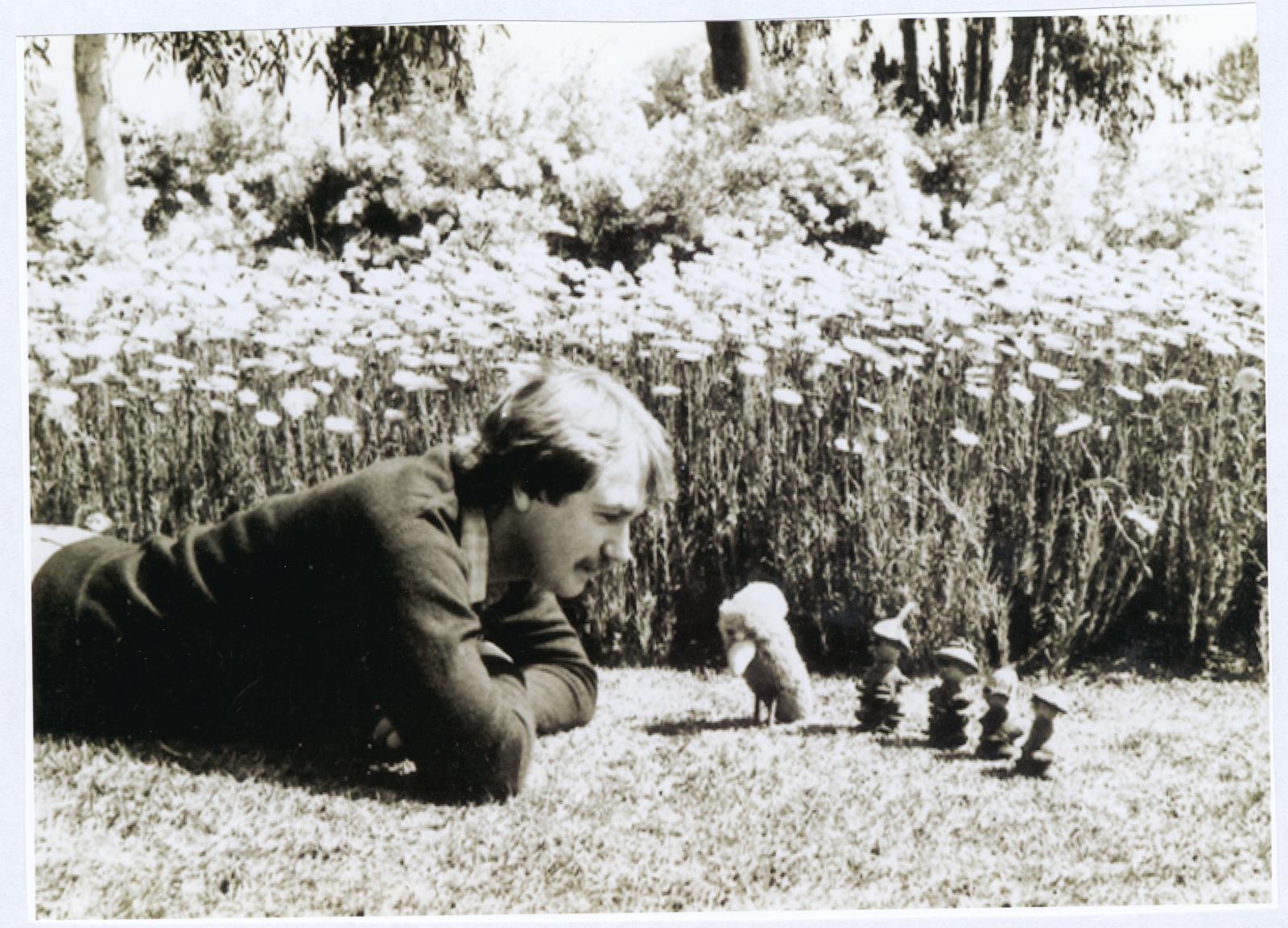 Chris Trump lying in a garden looking at gumnut figures.