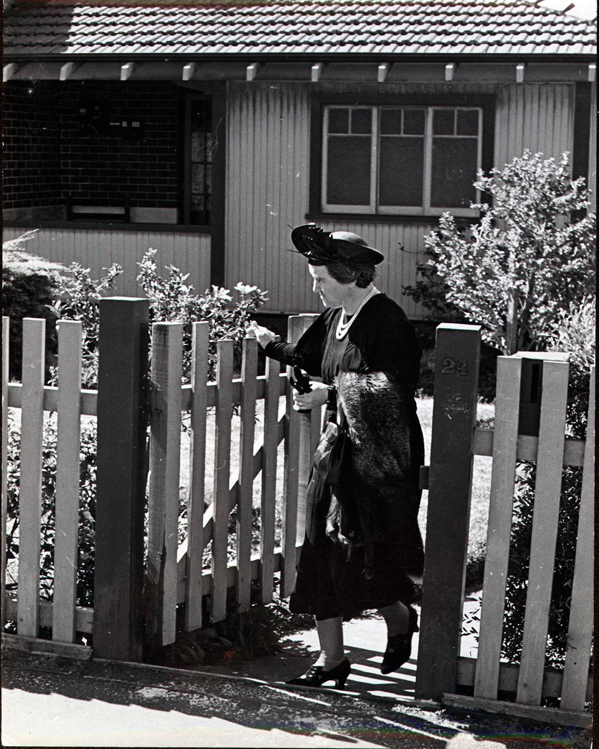 Women at the gate of a picket fence. 