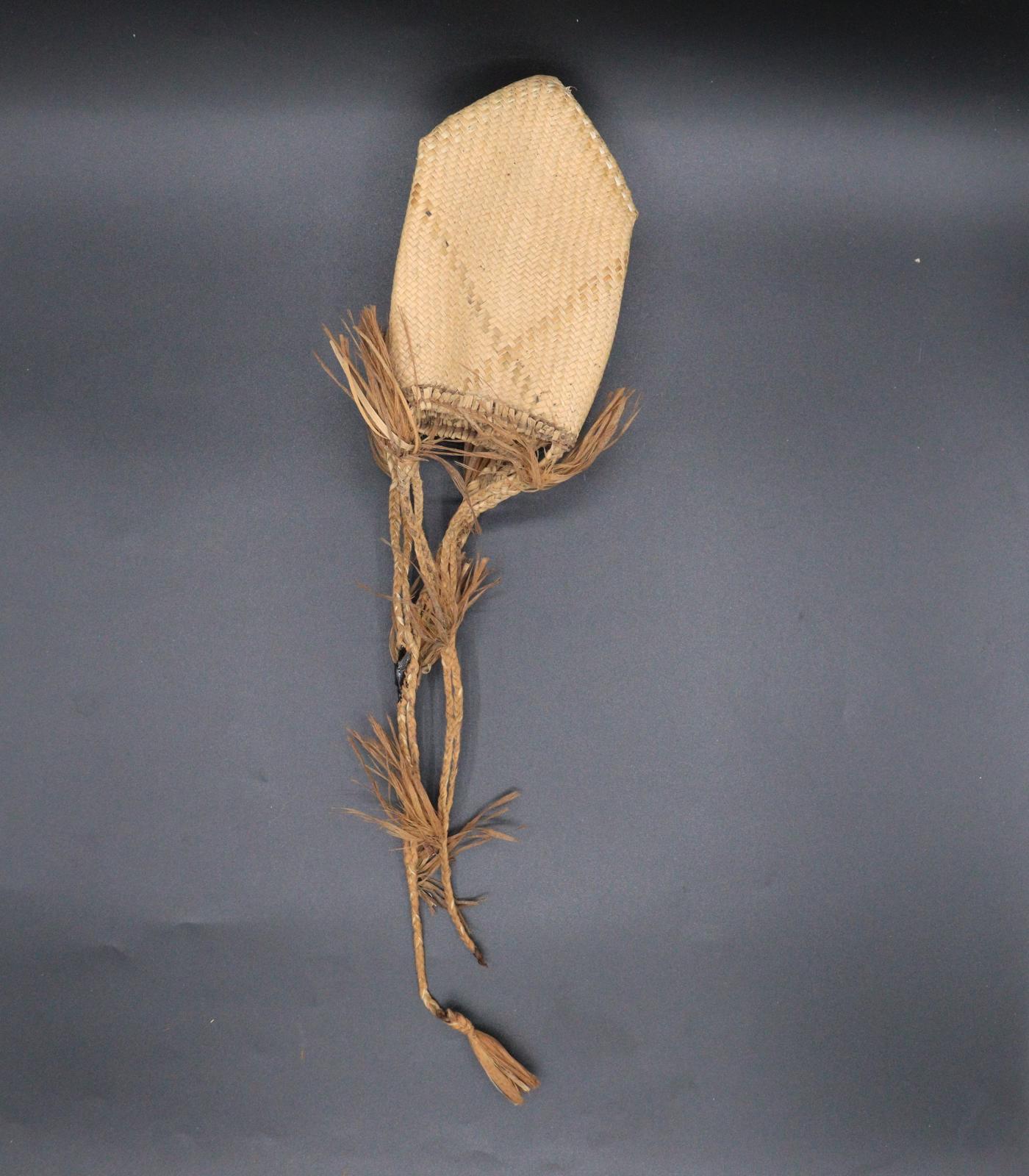 A small square woven grass bag with a fringe around the top.