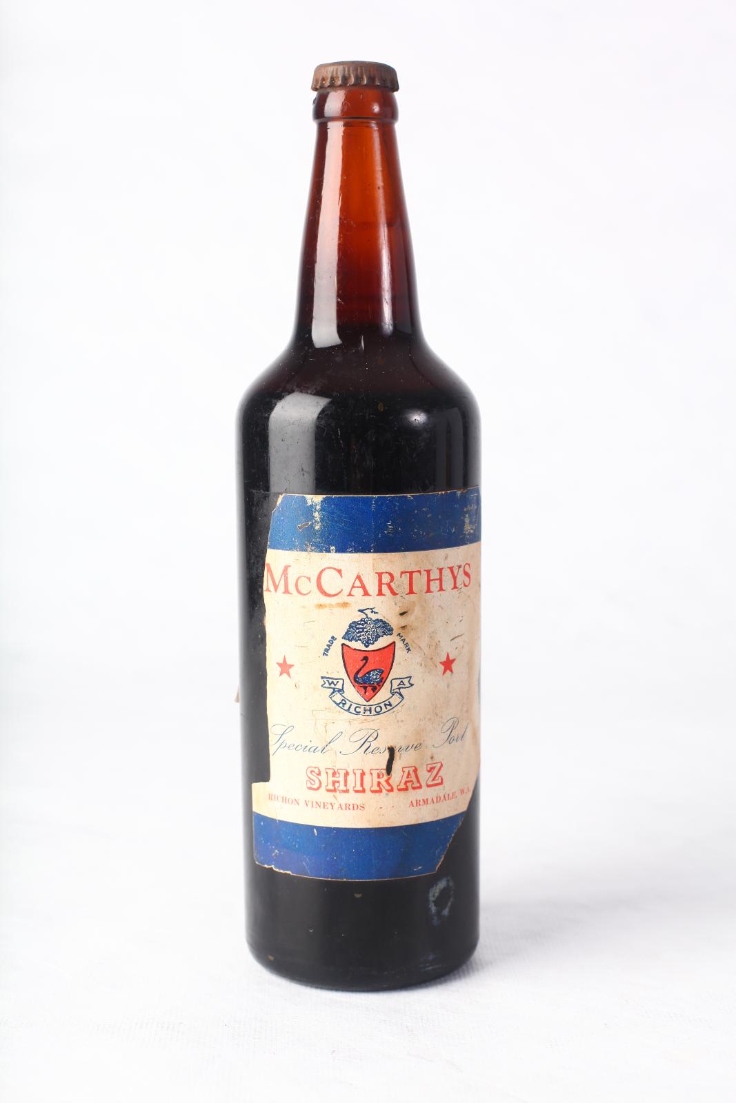 glass cylindrical wine bottle with metal cap and white label on front with the text  text 'McCARTHYS W.A. Richon Special Reserve Port SHIRAZ RICHON VINEYARDS ARMADALE, W.A.' 