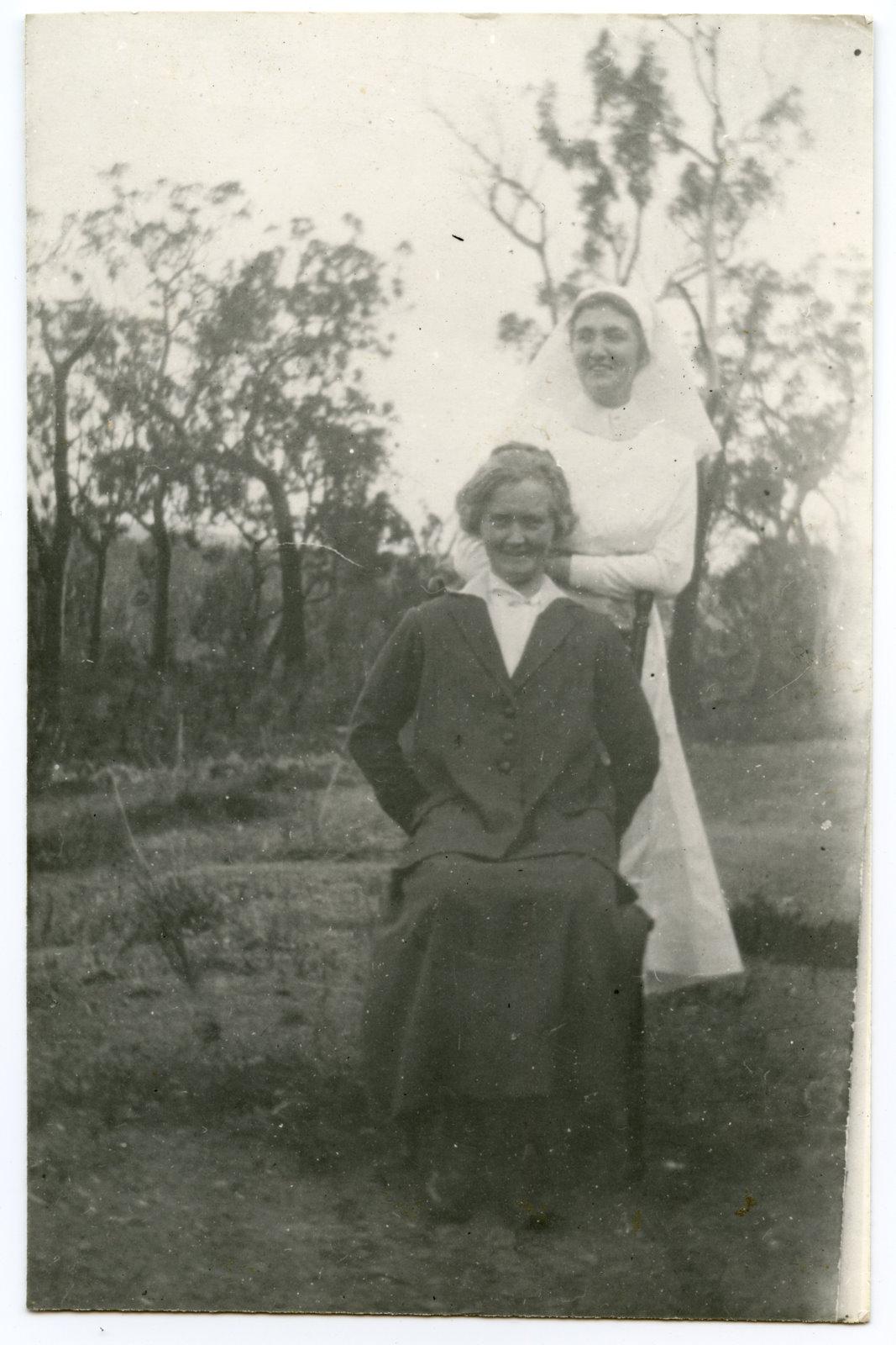 Two people in the bush, one dressed in a white uniform.