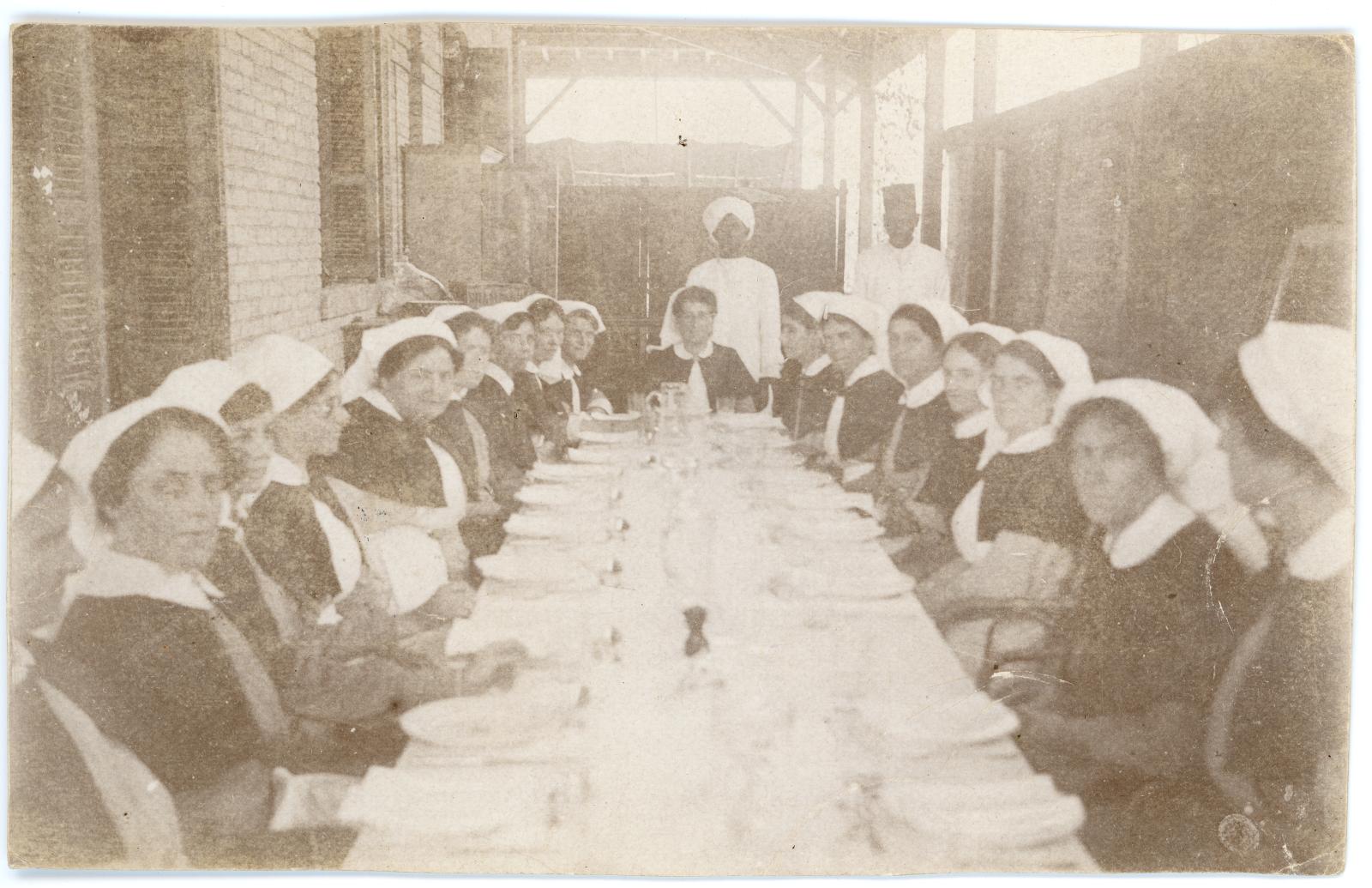 Australian nurses at the No.3 Auxiliary Hospital seated waiting for a meal.