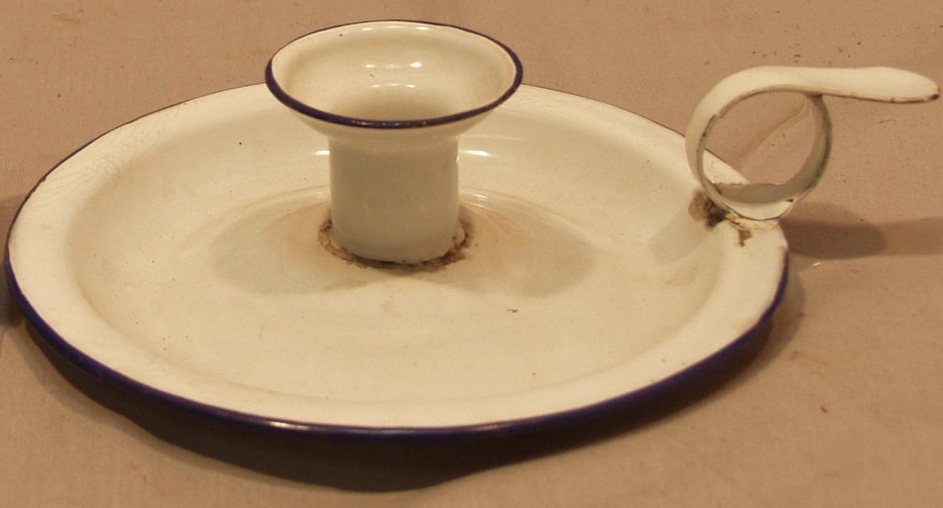 White enamel candle holder, with a round base and circular handle on the rim.