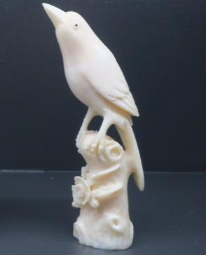 Whale tooth carved into the shape of a bird perched on a stand. 
