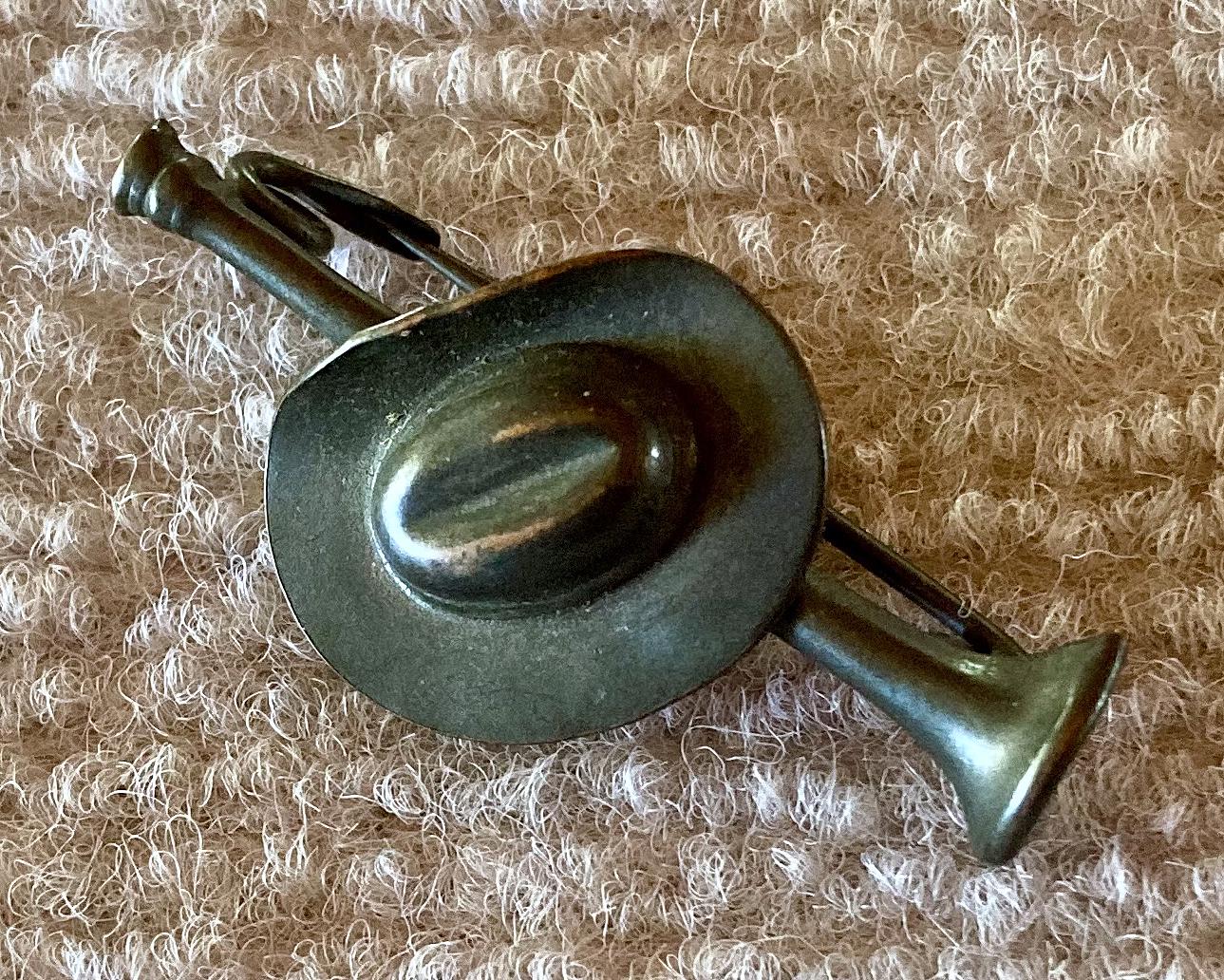 Angled view of metal slouch hat mounted on bugle sweetheart brooch