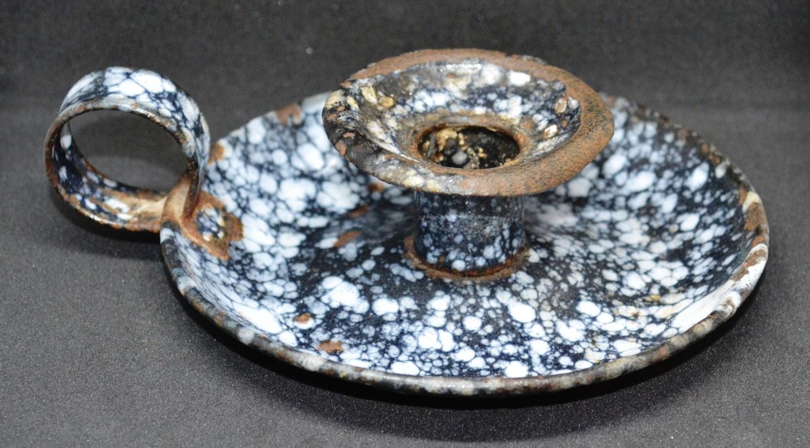 A small, mottled blue and white enamel candle holder with a wide, round base for catching wax.