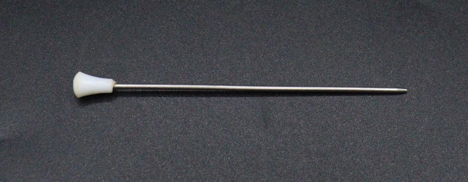 A single needle with a white plastic, conical handle at one end.
