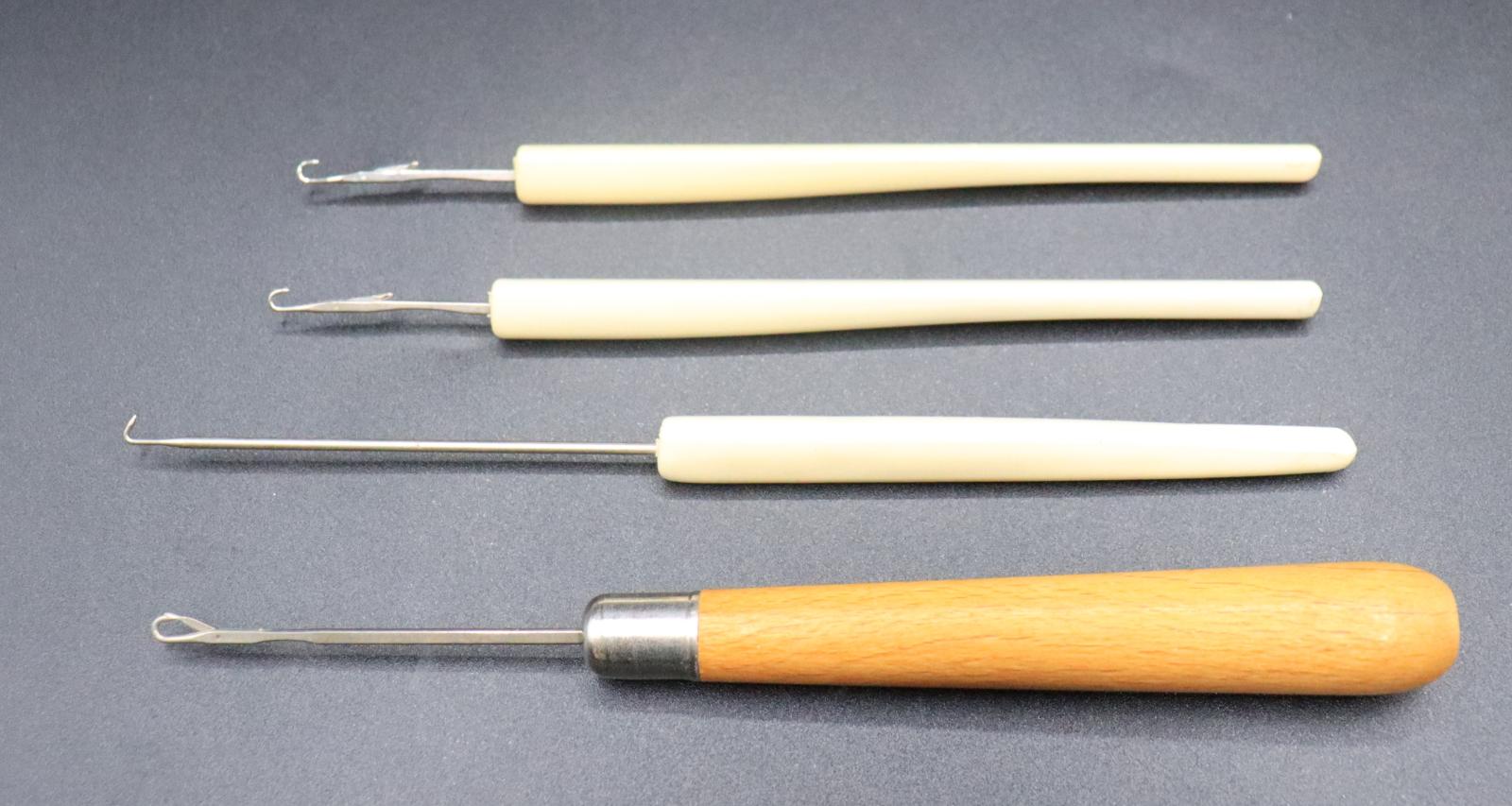 4 crochet hooks for the BROTHER knitting machine. 3 have a white plastic handle, the other has a rounded wooden handle.