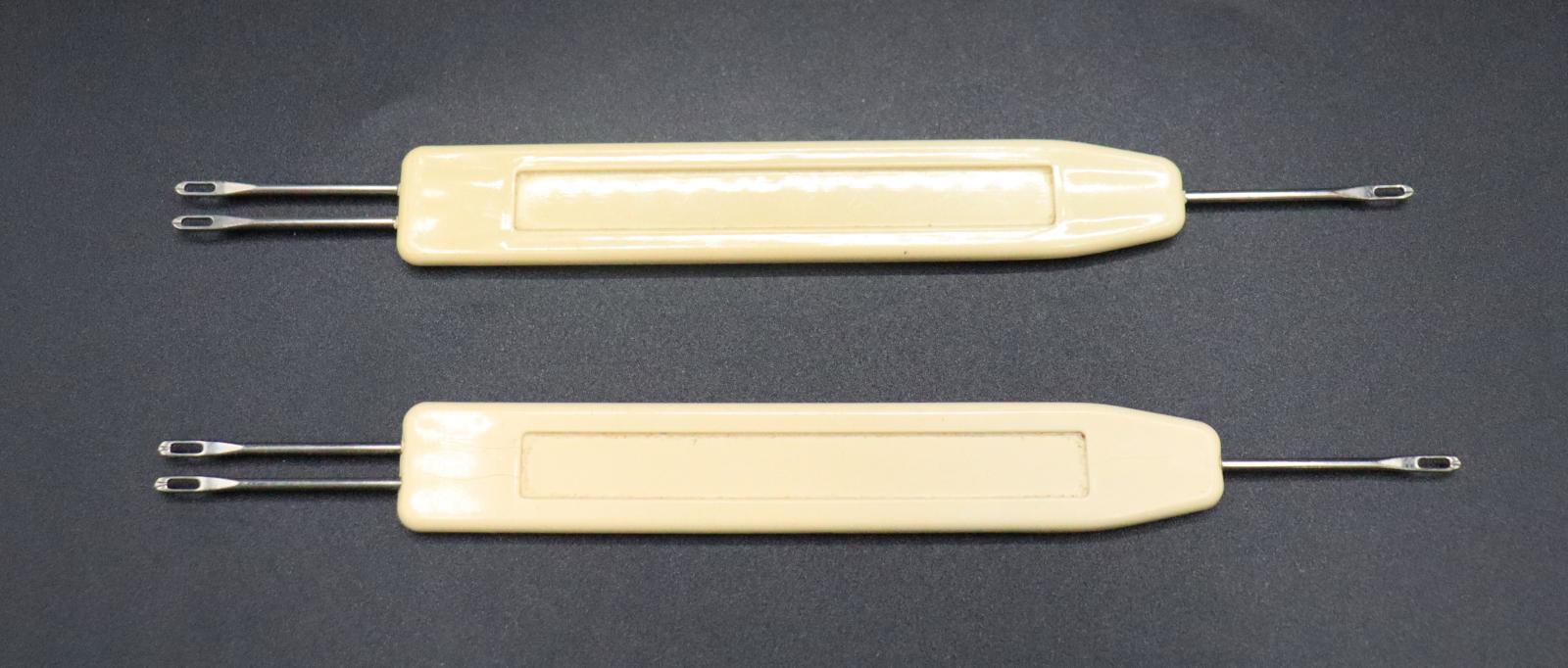 2 crochet hooks for the BROTHER knitting machine. Both have a flat, plastic handles. One end of the tools has 2 looped needles, the other end has just one.