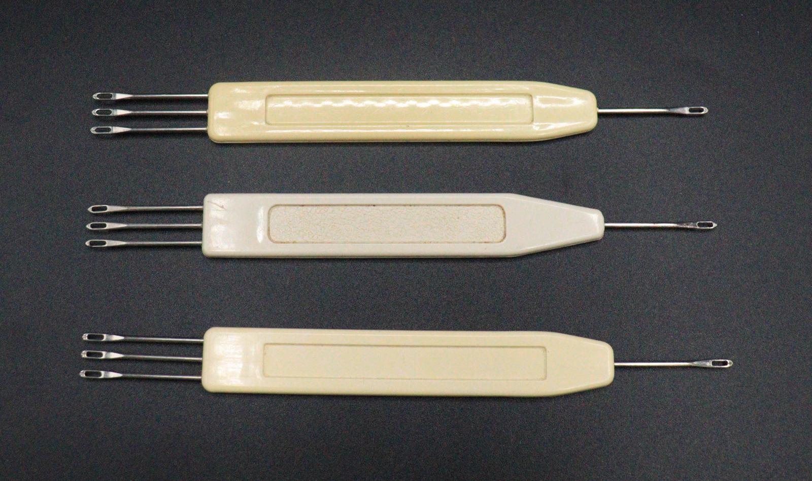 3 crochet hooks for the BROTHER knitting machine. Both have a flat, plastic handles. One end of the tools has 3 looped needles, the other end has just one.