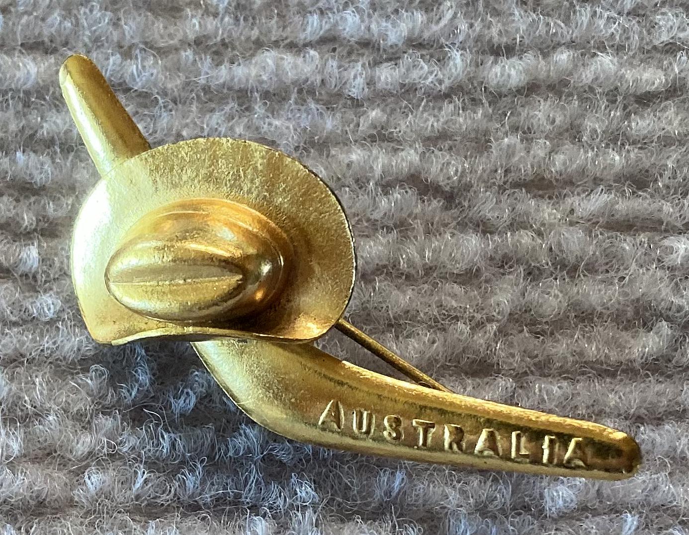 Angled view of gold tone patriotic brooch with slouch hat and boomerang