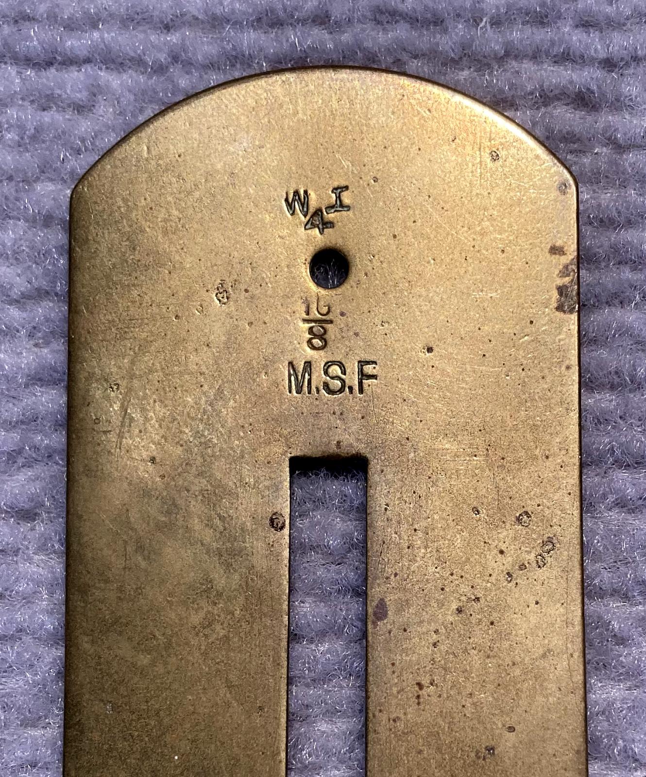 Close up of maker's marks on WWI era brass button stick 