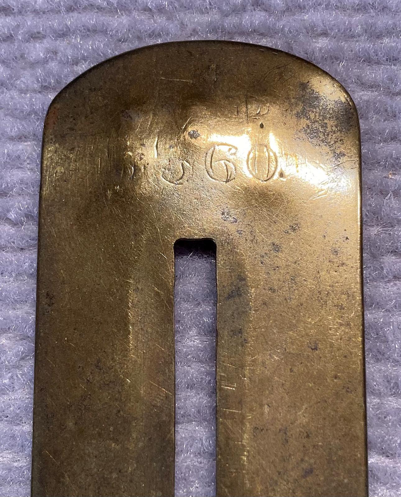 Close up of reverse of antique brass button stick showing engraved numbers