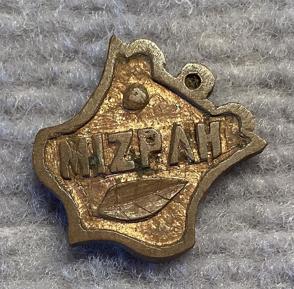 Angled view of gilded metal Mizpah sweetheart fob or pendant