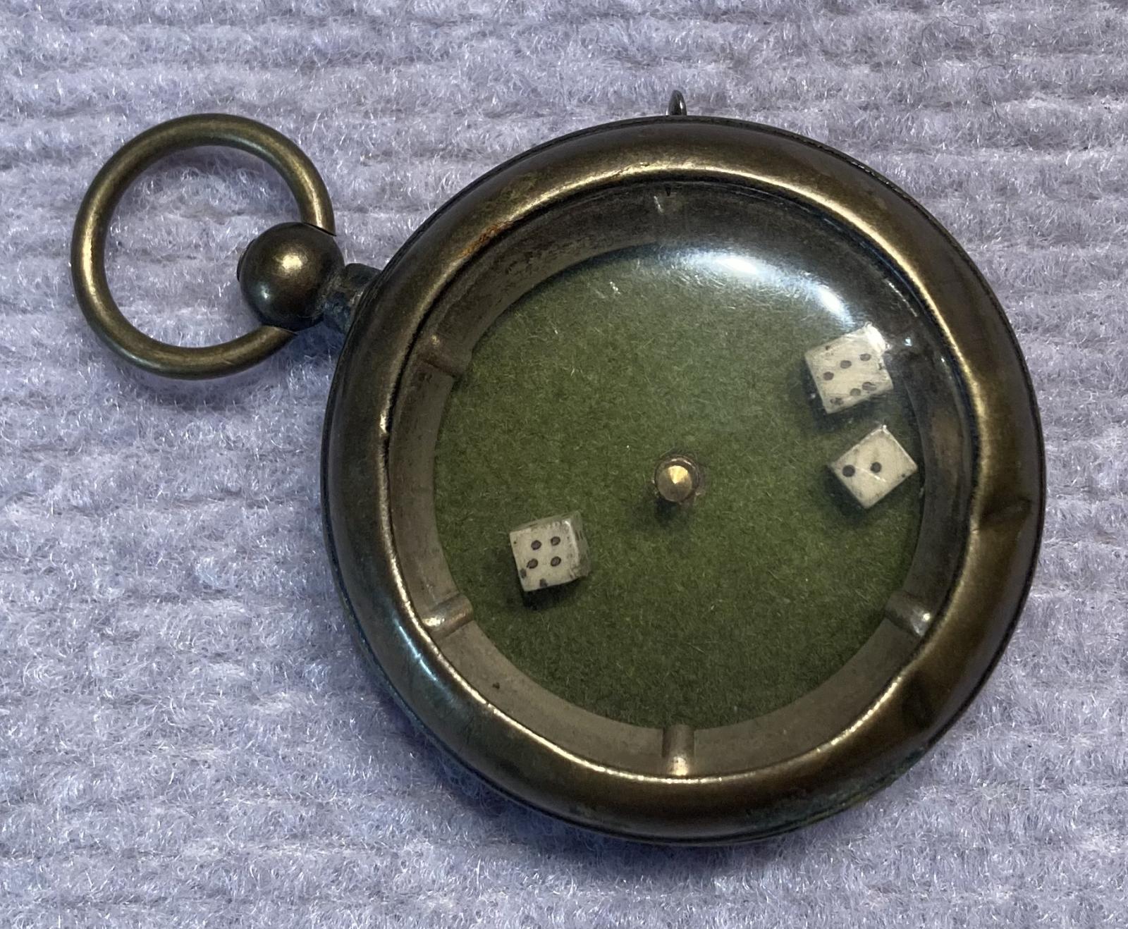 Angled view of mechanical dice game encased in a pocket watch housing