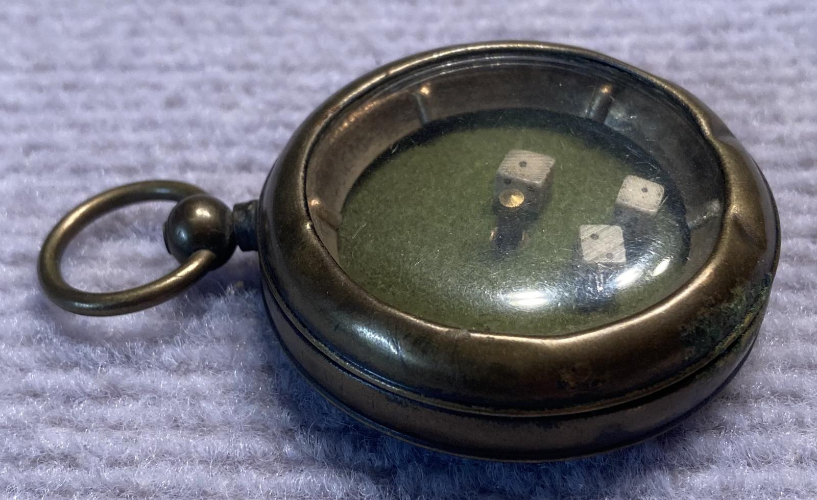 Side view of mechanical dice game encased in a pocket watch housing