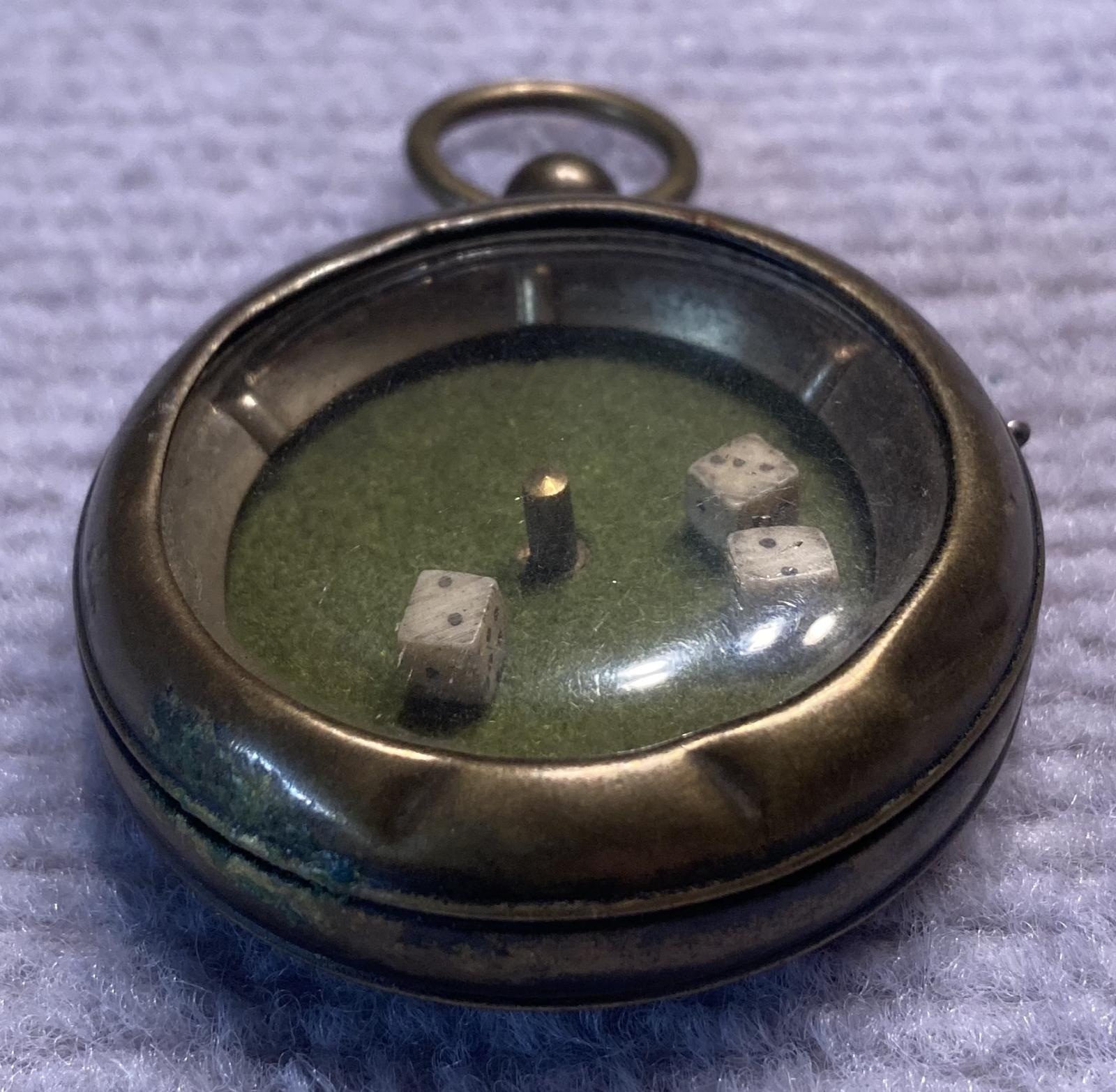 Oblique view of mechanical dice game encased in a pocket watch housing