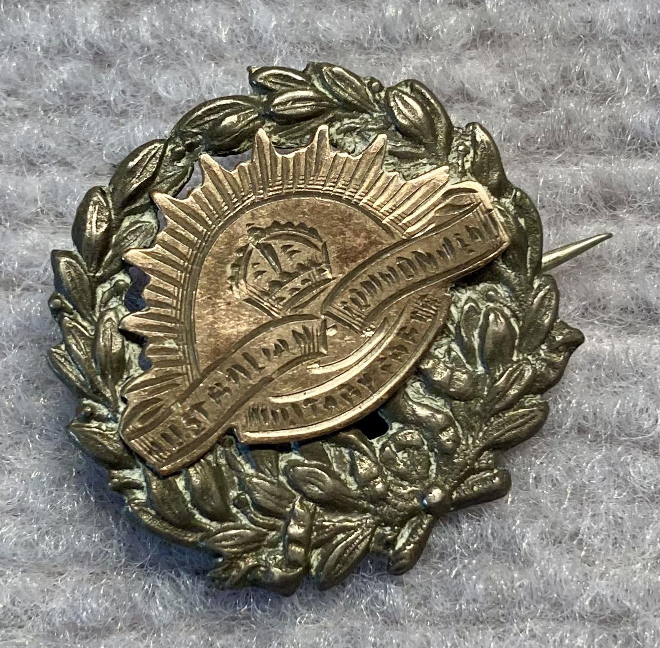 Angled view of metal sweetheart brooch featuring a Rising Sun badge on a wreath