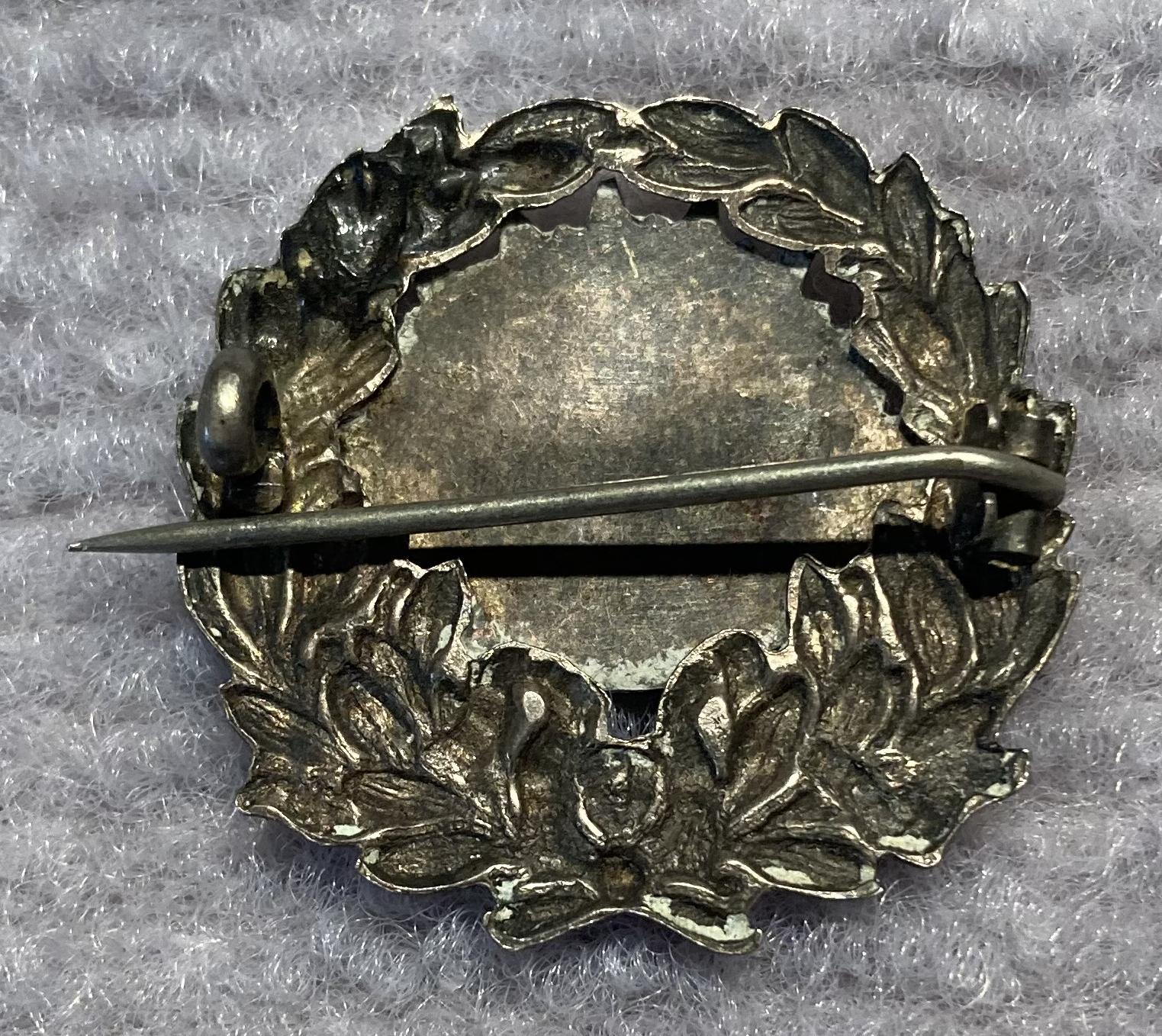 Reverse of metal sweetheart brooch featuring a Rising Sun badge on a wreath