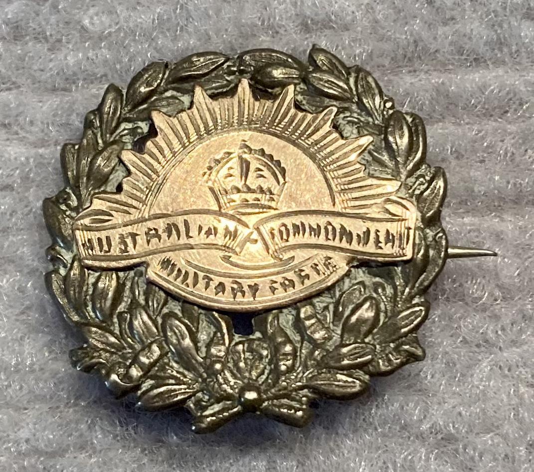Metal sweetheart brooch featuring a Rising Sun badge on a wreath