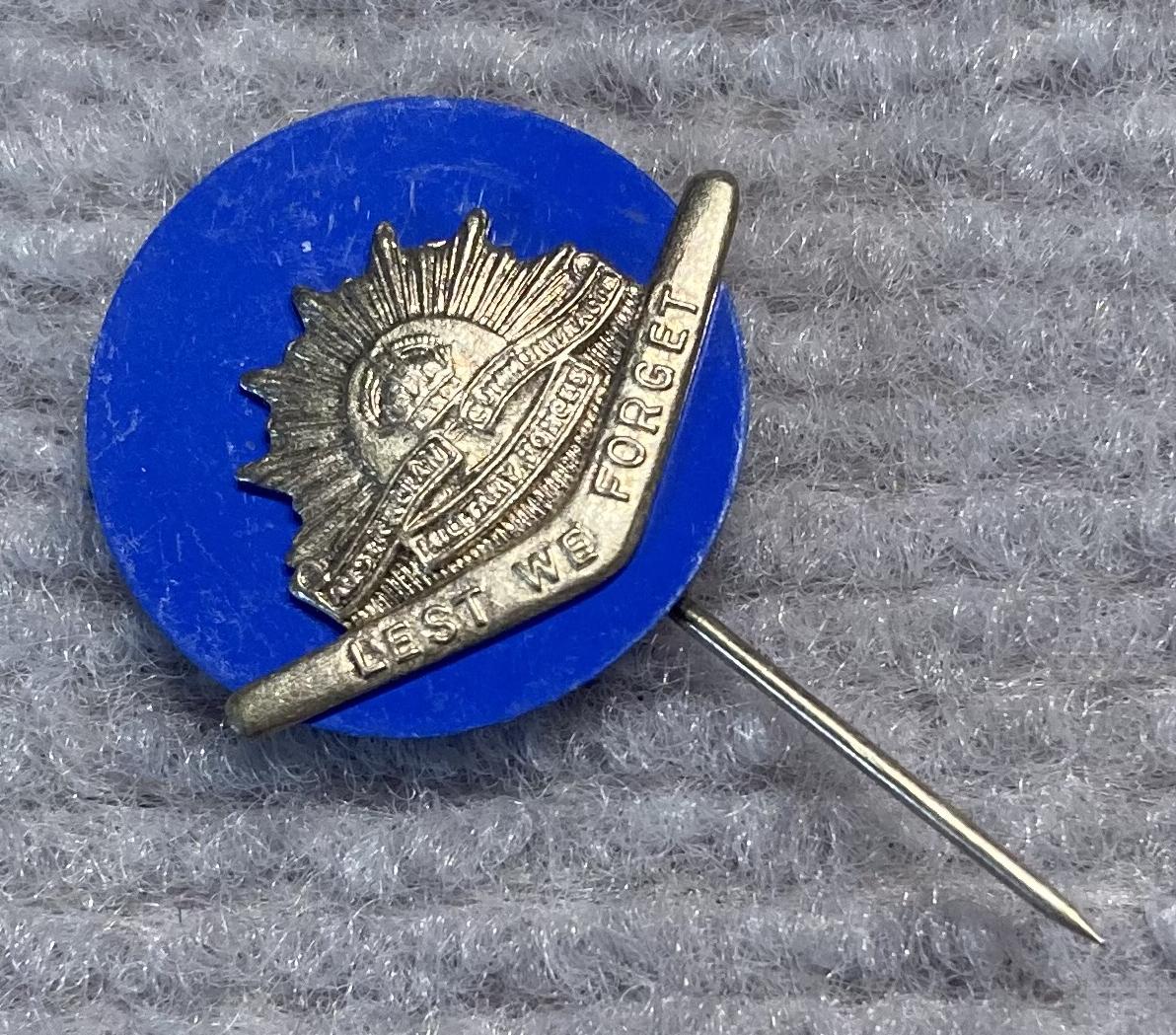 Angled view of miniature Rising Sun badge and boomerang stick pin on blue backing