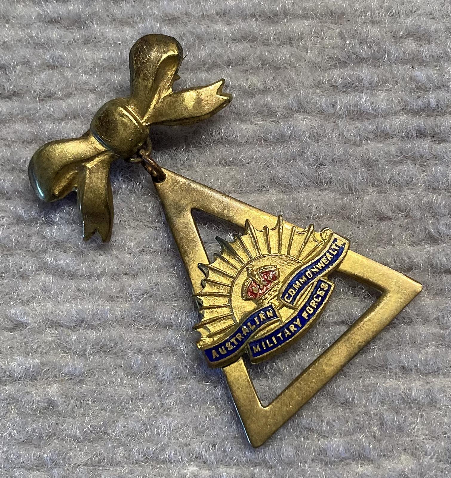 Angled view of gold tone metal and enamel Rising Sun badge sweetheart brooch