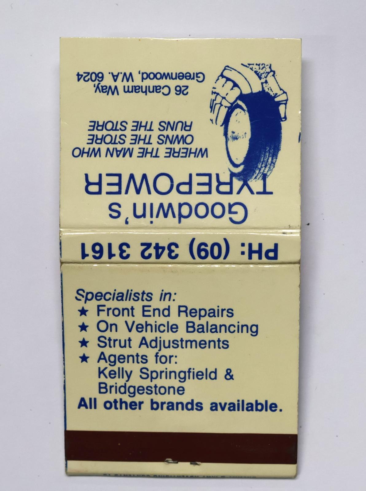 Square shaped matchbook with white coloured background and blue text and image. The back of the matchbook has a brown igniting panel.  