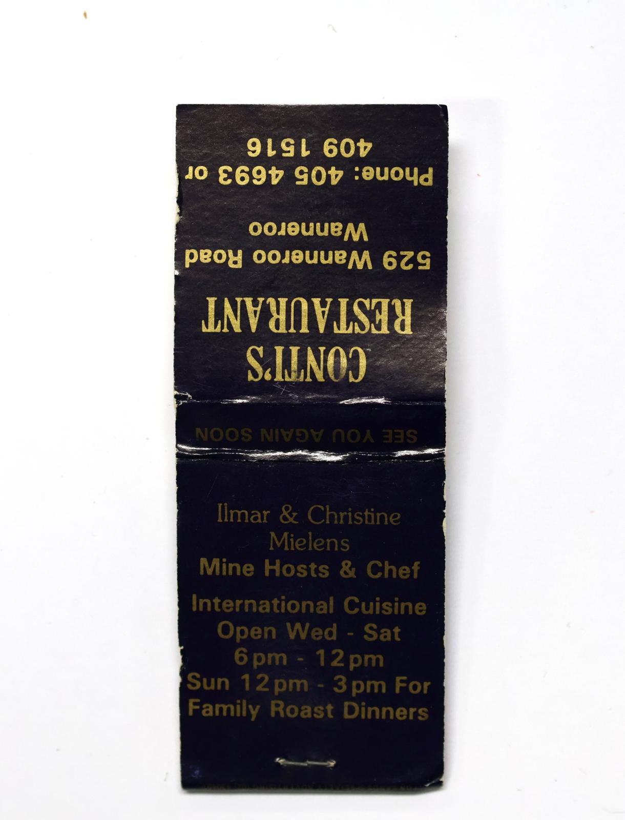 Rectangular shaped matchbook with dark blue background and gold text.  The front of the matchbook has a brown igniting panel. 