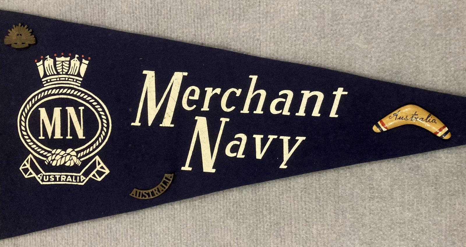 Close up of central section of souvenir felt naval pennant with attached badges - Merchant Navy 