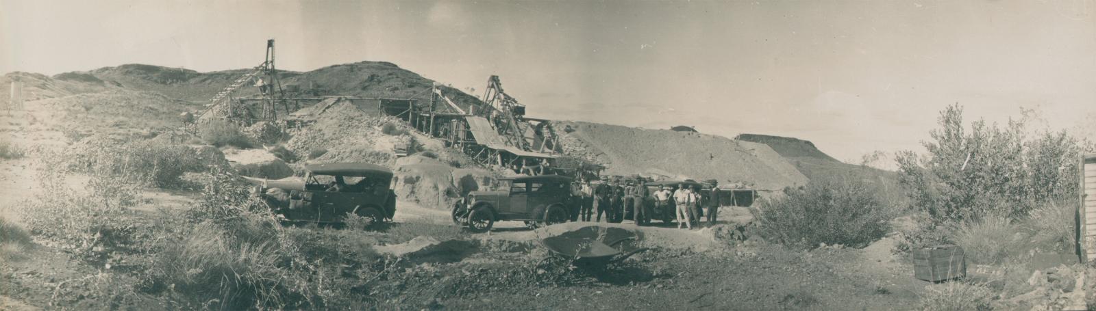 Group of men standing near cars, with Lionel Mine in the background.