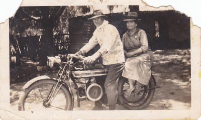 Black and white photograph of a man and woman astride a motorbike