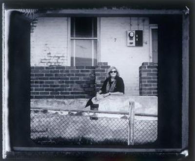 Black and white photograph of Pippin Drysdale sitting outside her home.
